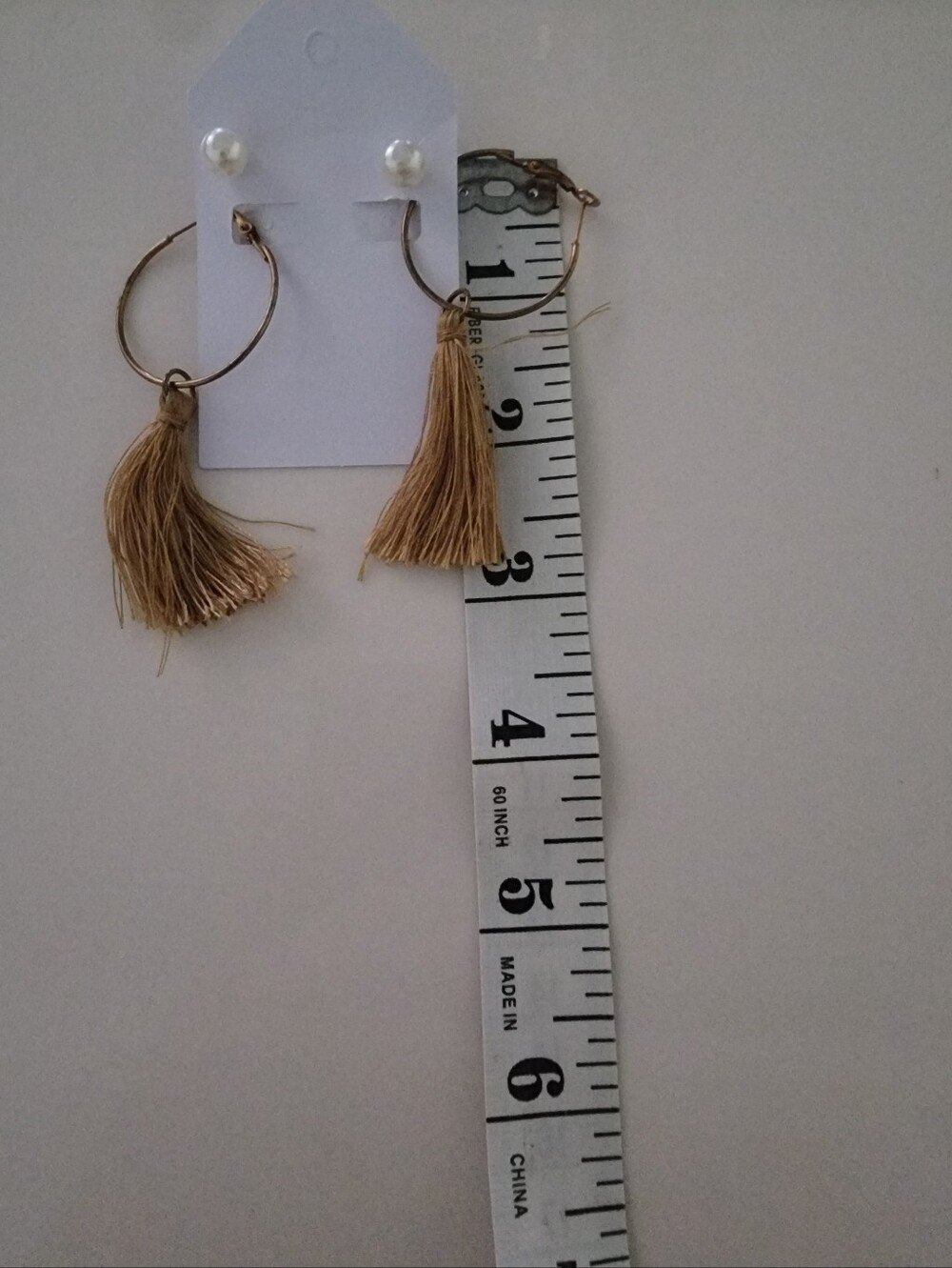 Tassel earrings feature a tan fringe dangling from thin gold-tone hoops.